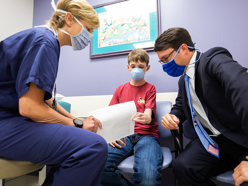 Dr. Kellie Leitch looks at Hunter Lindsay's hands and forearms during a follow-up visit.